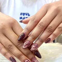 A bold and elegant design. This manicure features deep burgundy nails paired with accent nails showcasing delicate, hand-painted floral patterns in a matching shade.