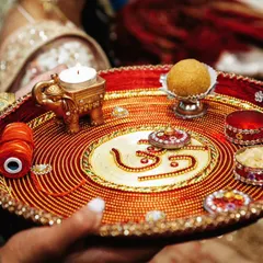 A close-up of a beautifully decorated puja thali, featuring the 'Om' symbol, a diya, and other ritual items.