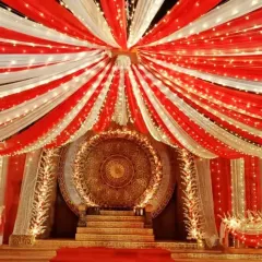 Here is a traditional stage I designed, perfect for a wedding reception or cultural festival. The design features extensive red and white fabric draping across the ceiling, intricate lighting, and a detailed golden centerpiece to create a rich, celebratory atmosphere.