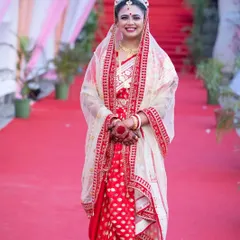 A full-length shot of a Bengali bride making her entrance, showcasing her complete bridal look with the 'topor' and veil.