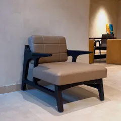 This sharp and sexy armchair features a dark wood frame treated with the Shou-Sugi-Ban technique and chocolate-colored leatherette upholstery. The stitch detailing adds a classic touch, making it perfect for a home office.