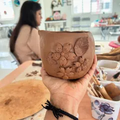 A beautifully detailed, hand-built pottery piece with floral embellishments, created in our workshop.