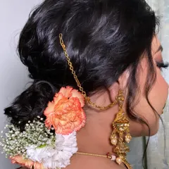 A close-up of this elegant bridal bun, decorated with fresh carnations and baby's breath. Floral buns are a beautiful way to add a touch of freshness and tradition to your wedding look.