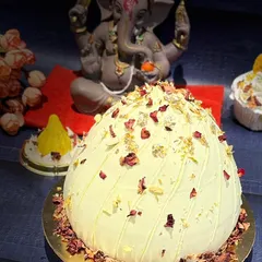 My grand modak cake, specially designed for Ganesh Chaturthi. This large, dome-shaped cake is flavored with traditional essences and decorated with edible rose petals and gold leaf.
