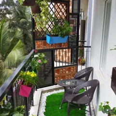 This balcony setup combines natural elements and comfortable seating. We used a mix of hanging plants, railing planters, and a wooden trellis to create a private, green retreat.