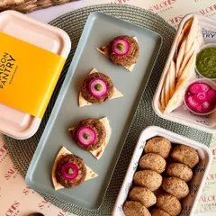 My ready-to-cook Galouti Kebabs are perfect for an easy yet impressive appetizer. The image shows the kebabs before and after cooking, served on mini flatbreads with pickled onions and mint chutney.