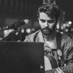 I hold my guitar behind a music stand in this close black-and-white performance portrait by @abhinsinghh.