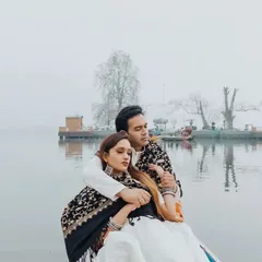 A romantic embrace on a boat, with the serene, foggy landscape of Kashmir creating a dreamy and ethereal atmosphere. This is a perfect example of a cinematic couple portrait.