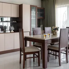 The dining area in the same home includes an expansive crockery and bar unit with mirrored accents and fluted glass. The walnut wood and neutral tones create a cohesive flow from the living space.