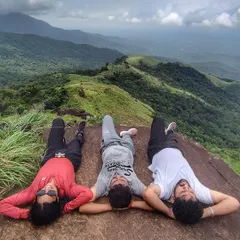 Taking a well-deserved rest at the summit of the Kurinjal trek, with panoramic views of the shola grasslands.