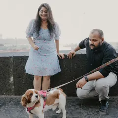A candid moment during a Mumbai pre-wedding shoot where the couple is interacting with their charming Cavalier King Charles Spaniel. Including pets makes the session feel even more personal and fun.