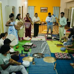 A group of students exploring a variety of instruments together. You can see the joy and curiosity as they experiment with frame drums, rainsticks, and more during a jam session.