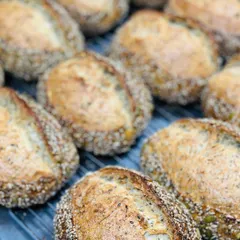 Our freshly baked seeded country loaves, cooling on a rack. These loaves are packed with a variety of seeds, offering a wholesome texture and nutty flavor.