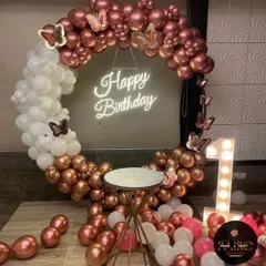 An elegant birthday ring decoration in rose gold and white. The arch is adorned with butterfly cutouts and features a "Happy Birthday" neon sign and a light-up number "1".