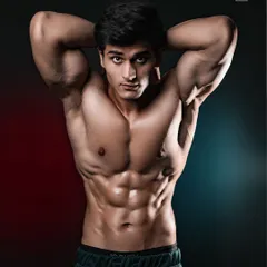 A modern athletic portrait using dual-tone red and blue lighting to add mood and dimension. The focus is on sharp abdominal definition and a confident, direct-to-camera pose for a high-impact fitness portfolio shot.