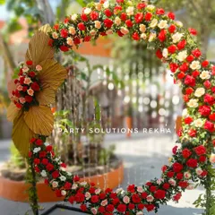 A beautiful circular floral arrangement of red and white roses, accented with golden dried palm leaves. This makes for a stunning photo backdrop or stage element.