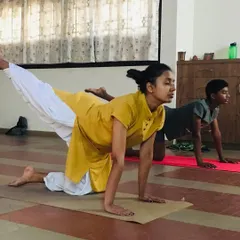 Teaching is a partnership. In this photo, I am guiding a young student through a posture during a kids' yoga session. I ensure each child receives personal attention to help them with alignment and to make sure they are practicing safely and effectively.