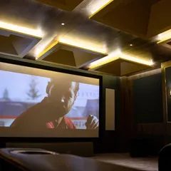 This angle shows the importance of professional design in a home theatre. The coffered ceiling contains acoustic treatments while the sconce lighting adds to the cinematic ambiance, all controlled with a single touch.