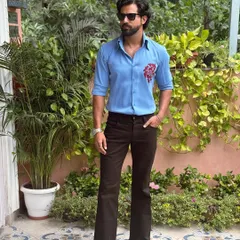 Our hand-painted blue shirt, styled with dark flared trousers in a lush garden setting. It's the ideal look for a stylish brunch or daytime gathering.