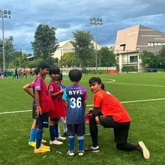 Our AFC-certified coaches are experts at connecting with young children. A coach kneels down to chat with our youngest players, showing the patient, encouraging, and hands-on guidance we provide in every session to build confidence.