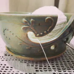 A happy knitter using their custom-made yarn bowl. I designed this piece with a special swirl to guide the yarn and decorative carvings, making it both a practical tool and a beautiful object for their craft corner.