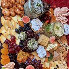 This overhead view showcases the richness and variety of our grazing platters. We incorporate diverse textures and flavors, including fresh figs, grapes, assorted crackers, cheese balls, and cured meats for a complete sensory experience.