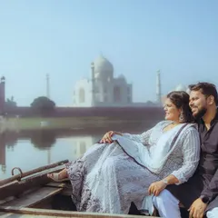 Another beautiful shot from the Yamuna river, capturing the couple relaxing as they float past the iconic monument. This showcases a relaxed, candid moment during a destination shoot.