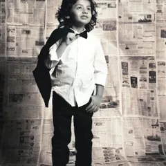 This little gentleman is looking sharp, casually slinging his jacket over his shoulder for a classic portrait.