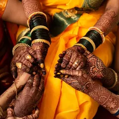 A candid shot of the bride and her bridesmaids, their hands intertwined. This photo captures the beauty of shared traditions and the bond between friends on a wedding day.