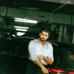 A confident portrait against a car, where the subject engages directly with the camera. The cool tones and industrial background add to the modern, urban feel.