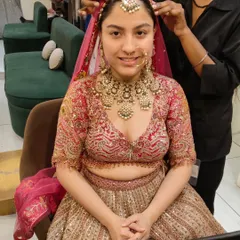 Getting the final touches right. This bride is having her maang tikka and nath adjusted, completing her look with a heavy, traditional gold and pearl bridal jewellery set.
