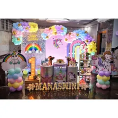 A dreamy unicorn and rainbow themed party for a first birthday. The decor features a silver sequin backdrop, a pastel rainbow balloon arch, unicorn cutout's, and marquee letter's for the name 'Manasvini'.