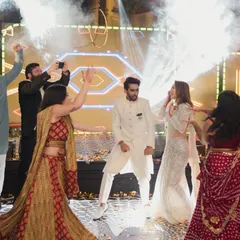 The couple takes center stage on the dance floor, surrounded by friends and jets of smoke for a high-energy Sangeet performance. I design the event flow to keep the energy up all night.