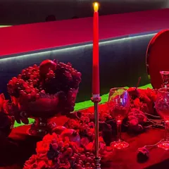 The tablescape for the Ajio Luxe gala was a study in monochrome luxury. We used deep red florals, fruits like grapes and pomegranates, and tall taper candles to create a dramatic, immersive dining experience under intense red lighting.