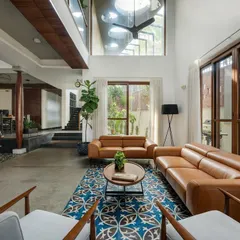 Another view of the living area, highlighting the interplay of textures. The cool concrete floor is balanced by the warmth of the leather sofa and the vibrant pattern of the Athangudi tiles, adding a touch of vernacular craft to the modern space.