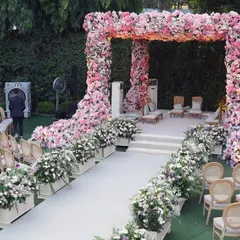A magnificent outdoor mandap completely covered in a gradient of pink and peach flowers. The grand scale and lushness of the floral design create a stunning focal point for a garden wedding ceremony.