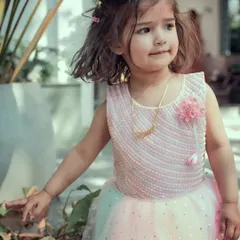 A candid shot of a little girl in her party dress, looking curious and sweet. Our approach to kids' photography is to let them be themselves, resulting in honest and charming pictures.