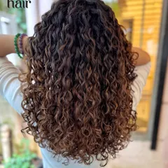 Adding dimension with a brunette balayage. These lighter pieces are strategically placed to catch the light and make the curls pop without a full head of colour.