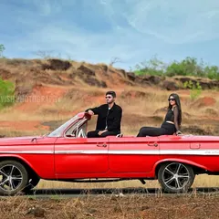 A stylish pre-wedding shoot featuring a couple with a vintage red convertible against a rustic, open landscape. This showcases my ability to arrange unique props and locations for a cinematic feel.