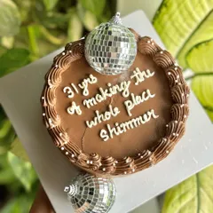 "31 yrs of making the whole place shimmer." This fun chocolate birthday cake is topped with disco balls, perfect for someone who adds a little extra sparkle to life.