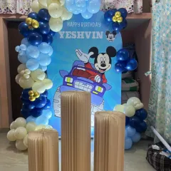 A fun Mickey Mouse monster truck theme for Yeshvin's birthday, featuring a blue and white balloon arch and classic cartoon fun.