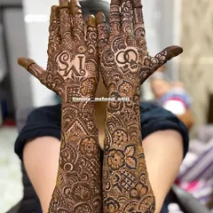 A full view of the 'MS' engagement mehendi, showcasing the symmetrical yet unique designs on both arms, extending all the way to the elbows.