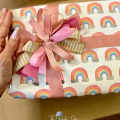 The art of wrapping is a passion of mine. Here, I've used a cheerful rainbow-print paper and layered multiple ribbons in coordinating colors to create a beautiful, textured bow.