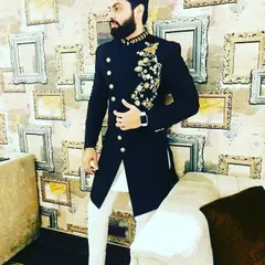 A smart black Indo-western jacket with asymmetrical buttons and gold floral embroidery on the shoulder and chest. Paired with white trousers, this is a sharp look for a sangeet or reception party.