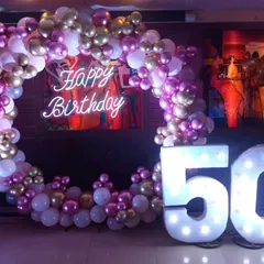 This 50th birthday design is all about glamour. A full balloon ring in shades of pink, white, and gold chrome surrounds a neon sign, complemented by large light-up '50' numbers for a truly dazzling effect.