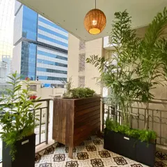 This custom-designed wooden bar cabinet provides stylish outdoor storage. The slatted design is modern and functional, and it serves as a beautiful base for displaying plants and decor against the urban backdrop.