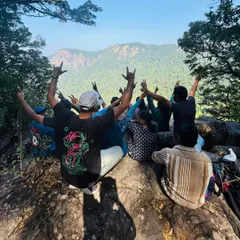 A group of trekkers celebrating at a viewpoint on the Narasimha Parvatha trail, with the Agumbe hills in the background.