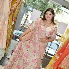 A client trying on a lovely peach and pink floral embroidered lehenga in the store. This is a great option for bridesmaids or as a wedding guest outfit.