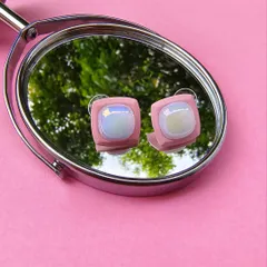 A product shot of the pink enamel square earrings, as seen on Karishma Tanna, reflected in a mirror.