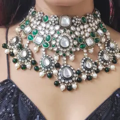 A product shot of a heavy Polki and Kundan choker set with green and white stones, showcasing the intricate craftsmanship.